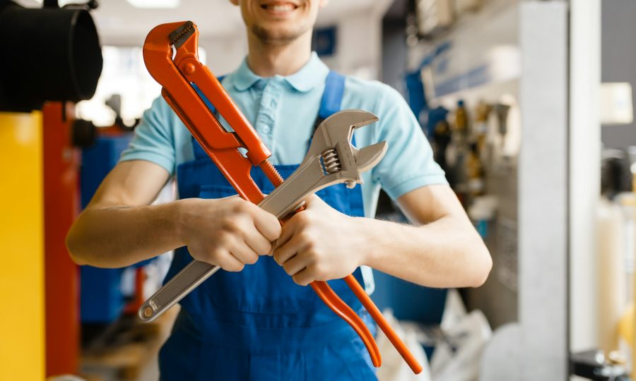 Plumber poses with pipe wrenches, plumbering store